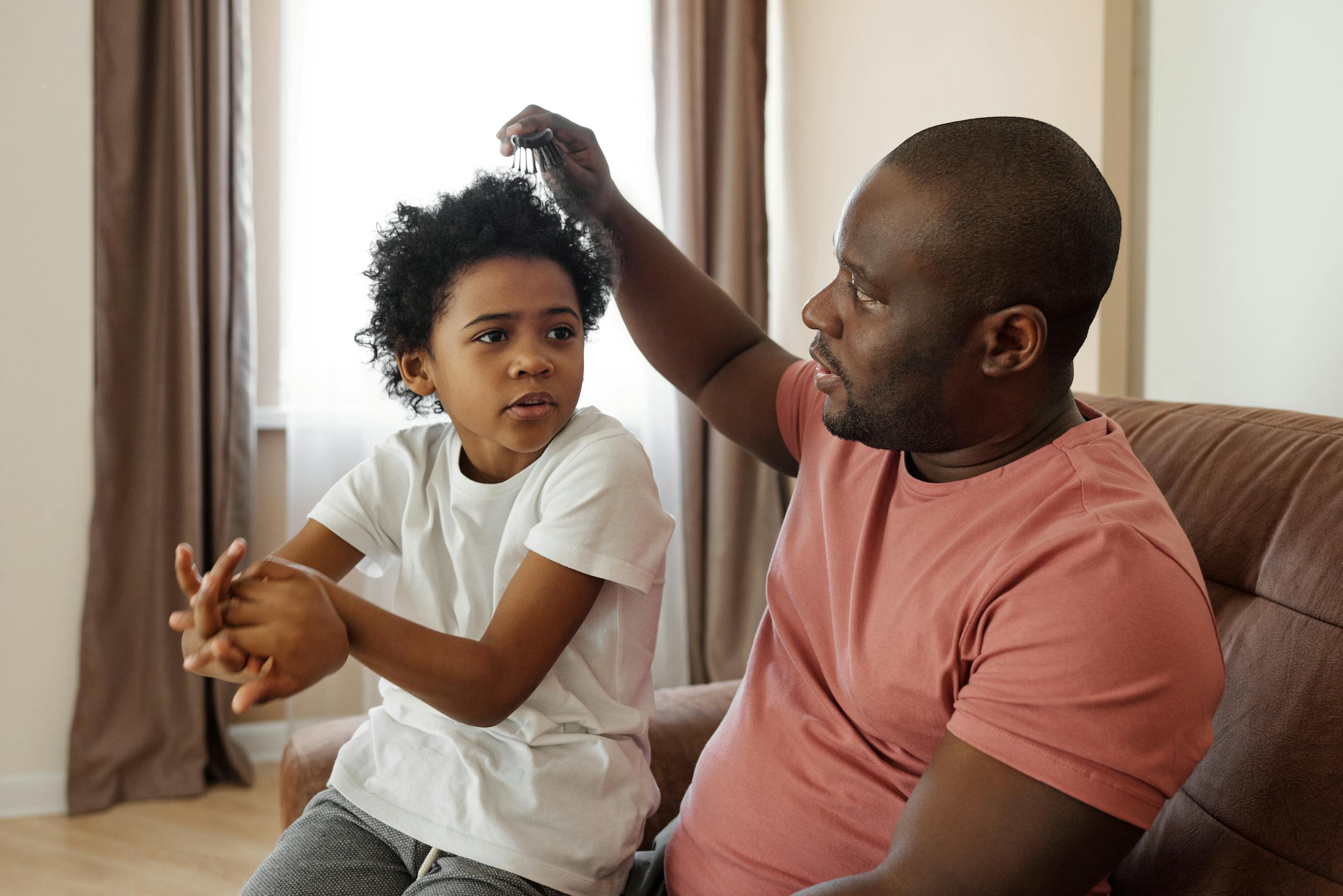 A father helps his son with hair brushing, creating a moment of bonding and family togetherness.